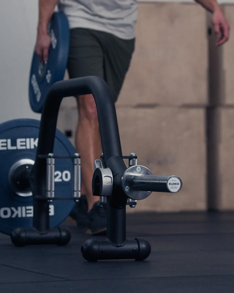 ELEIKO オープンカラー ブラックをバーベルシャフトに装着する動作を斜め横から捉えた構図。プレート横でレバー操作して固定するクイックロック機構が分かる使用シーン