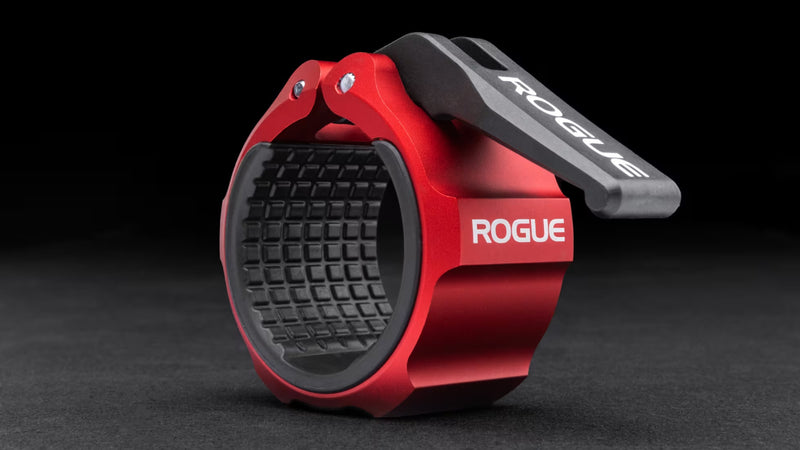 ROGUE USAアルミニウムカラー 2.0 レッドを斜め前方から捉え、ロックオープンナイロンレバーとCNC加工アルミボディ、内側ラバーライニング構造が分かるオリンピックバーベル用カラー