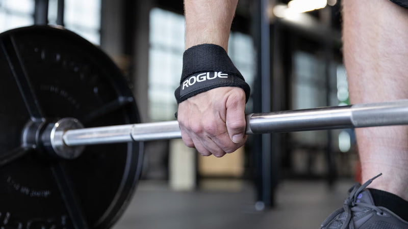 ROGUE ヘビーデューティー フィギュア 8 リフティングストラップ 2.0 ブラックを手首に装着しバーベルへ巻き付ける途中の動作を横から捉えた使用手順のロフティングストラップ